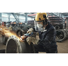 Ein Arbeiter schleift mit einer Flex ein Metallrohr, wobei Funken sprühen.