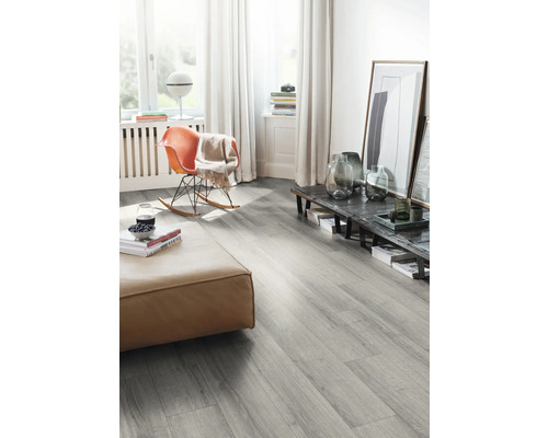 Wohnzimmer mit grauem Laminatboden, Sitzhocker und Schaukelstuhl.