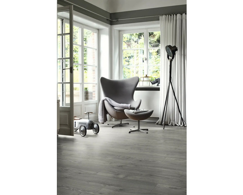 Heller Raum mit modernem Sessel, Stehlampe und grauem Vinylboden in Holzoptik