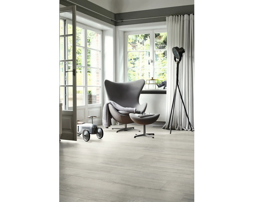 Heller Wohnraum mit Sessel, Leselampe und Spielzeugauto auf Holzboden