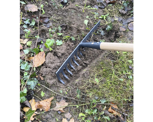Gartenrechen im Einsatz zum Einebnen von Erde im Garten.