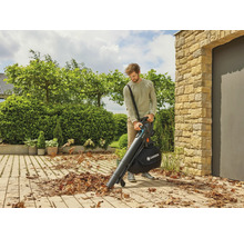 Ein Mann benutzt einen Laubsauger von Gardena auf einer gepflasterten Fläche, um Laub zu entfernen.