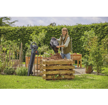 "Eine Frau leert einen Laubsack in einen Komposter aus Holzlatten