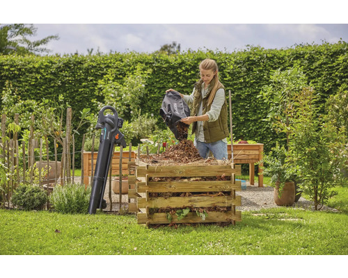 "Eine Frau leert einen Laubsack in einen Komposter aus Holzlatten