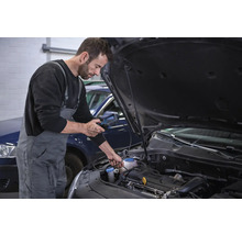 Ein Mechaniker führt eine Diagnose an einem Automotor mit einem Diagnosegerät durch.