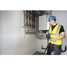 Handwerker verwendet einen Linienlaser zur Ausrichtung in einem Heizungsraum.