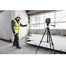 Handwerker mit Laser-Wasserwaage und Nivellierlatte bei der Installation eines Doppelbodens.