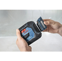 Bosch Logo. Eine Person wechselt die Batterien eines Kreuzlinienlasers.