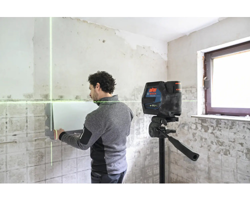 Ein Mann arbeitet mit einem Linienlaser in einem Raum.