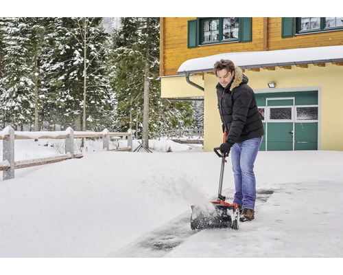 Mann räumt mit einer Schneefräse Schnee vor einem Haus