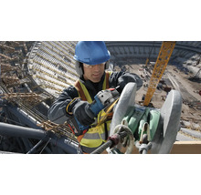 Ein Bauarbeiter schleift Metall mit einem Winkelschleifer auf einer Baustelle.