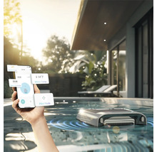 Person steuert Poolreinigungsroboter mit dem Smartphone in einem Außenpool