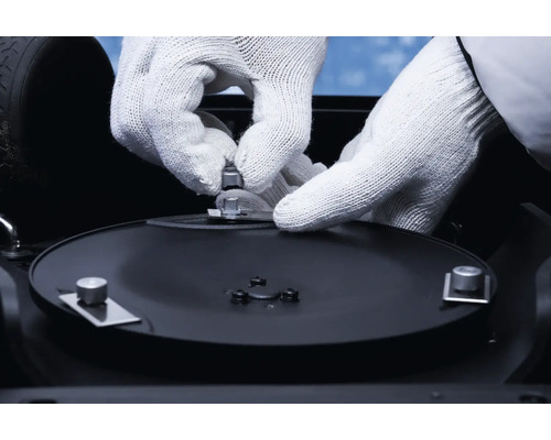 Hände mit Schutzhandschuhen befestigen Schrauben an einem Gerät.