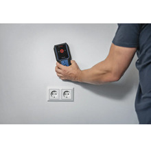 Eine Person verwendet einen Detektor von Bosch Professional, um nach Stromleitungen in der Nähe einer Steckdose zu suchen.