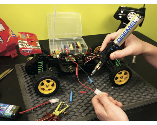 Reparatur eines funkgesteuerten Autos mit einem Lötkolben und Werkzeugen.