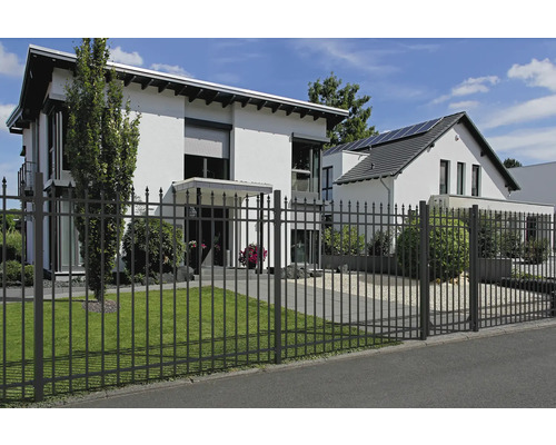 Metallzaun vor einem Wohnhaus mit Rasenfläche