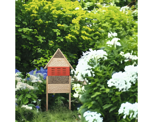 Insektenhotel aus Holz im Garten zwischen Pflanzen