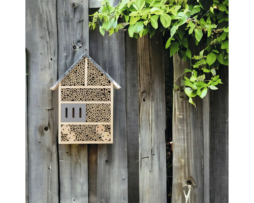 Insektenhotel aus Holz und Bambus an einem Holzzaun