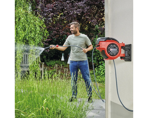 Mann benutzt eine Einhell Schlauchtrommel mit Wasserschlauch zur Gartenbewässerung.