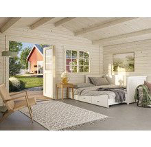 Innenansicht eines Holzhauses mit Bett, Teppich und geöffneter Tür zum Garten