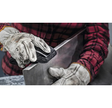 Eine Person reinigt mit einer Bürste ein Metallstück.