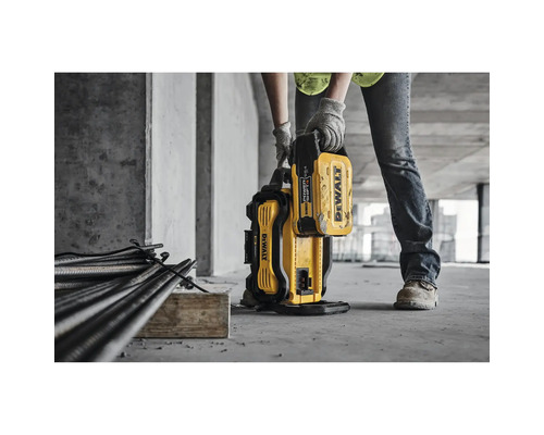 Eine Person trägt eine gelbe Dewalt Akku-Bewehrungsschere in einer Baustelle.
