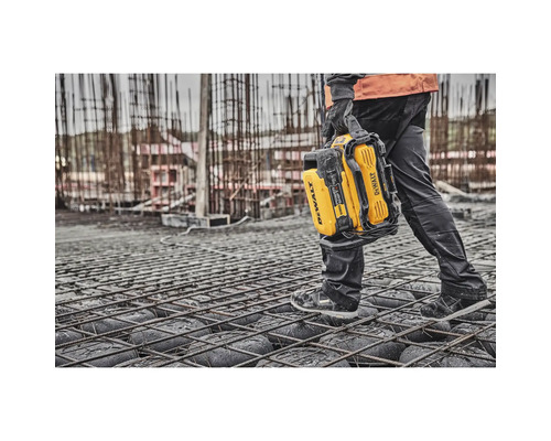 Eine Person trägt eine gelbe DeWalt Powerstation auf einer Baustelle.