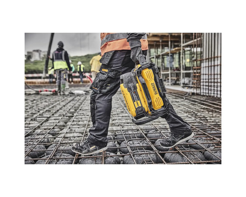 Bauarbeiter trägt tragbare DeWalt Arbeitsleuchte auf einer Baustelle.