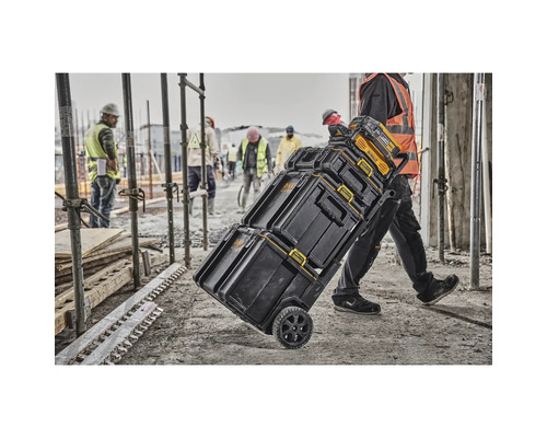 Person transportiert DeWalt Werkzeugkoffer auf Rädern auf einer Baustelle