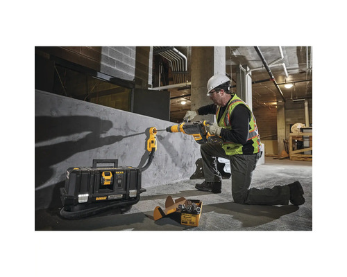 Ein Bauarbeiter bohrt mit einem Bohrhammer und Staubabsaugung ein Loch in eine Wand.