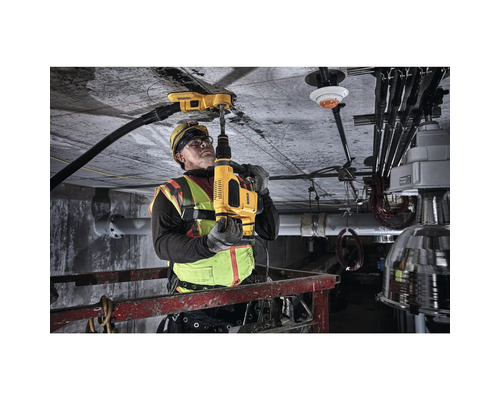 Ein Bauarbeiter bohrt mit einem Bohrhammer in eine Betondecke.