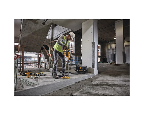 Ein Bauarbeiter verwendet auf einer Baustelle einen Bohrhammer der Marke DeWalt, um in einen Betonboden zu bohren.
