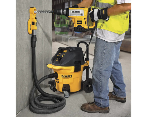 Mann bohrt mit Bohrhammer in Wand neben Staubsauger mit Absaugvorrichtung