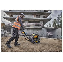 Ein Bauarbeiter verdichtet mit einer Rüttelplatte den Boden auf einer Baustelle.