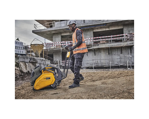 Ein Bauarbeiter bedient eine Rüttelplatte auf einer Baustelle.