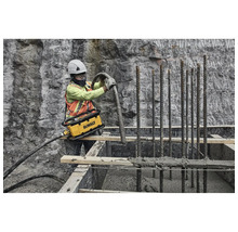Bauarbeiter verdichtet Beton mit einem Betonverdichter von DeWalt auf einer Baustelle.
