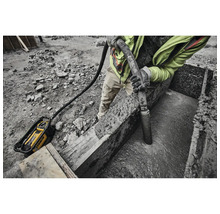 Mann verdichtet Beton mit einem Betonrüttler von DeWalt auf einer Baustelle.