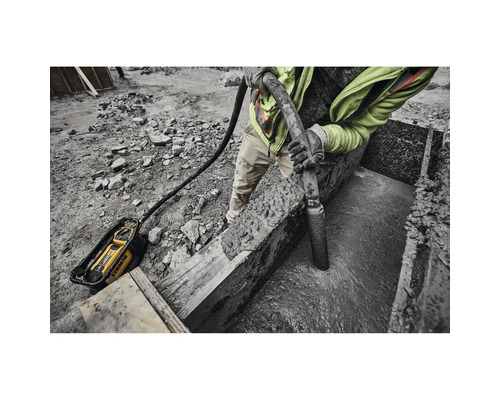 Mann verdichtet Beton mit einem Betonrüttler von DeWalt auf einer Baustelle.