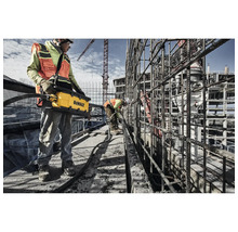Bauarbeiter verwenden einen Betonrüttler auf einer Baustelle.