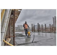 Ein Bauarbeiter verdichtet Beton mit einem DeWalt Betonverdichter auf einer Baustelle.