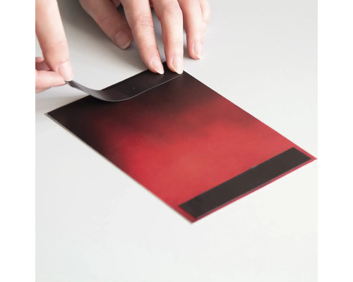 Hände ziehen Schutzfolie von einer roten Magnetfolie ab