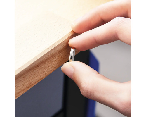 Eine Person hält ein dünnes, rundes Metallstück an eine Holzkante.