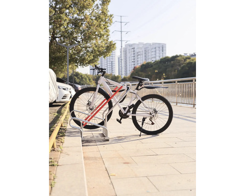 Ein weißes Fahrrad ist an einem Fahrradständer abgestellt.