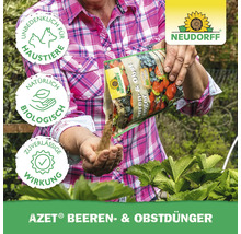 Frau düngt Beeren und Obst mit Azet Beeren- und Obstdünger von Neudorff. Das Produkt ist unbedenklich für Haustiere, natürlich und biologisch und hat eine zuverlässige Wirkung. Neudorff Logo.