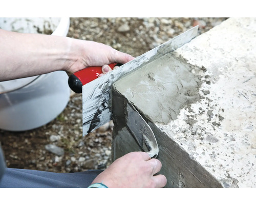 Eine Person glättet Beton mit einer Glättkelle.