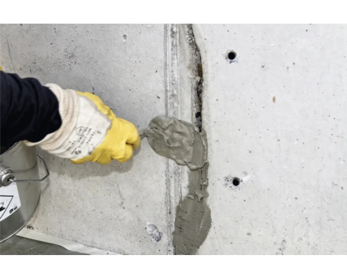 Handwerker füllt Riss in einer Betonwand mit Spachtelmasse