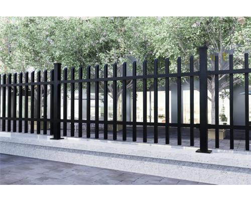 Metallzaun auf einer Betonmauer, mit Bäumen im Hintergrund