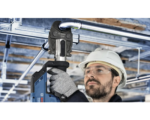 Ein Arbeiter mit Schutzhelm und Schutzbrille verwendet eine Bosch Presszange zur Installation von Rohren.