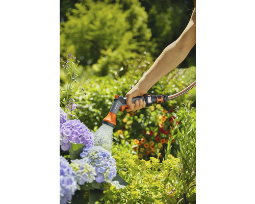 Eine Person bewässert Blumen mit einer Gartenausrüstung von Gardena.