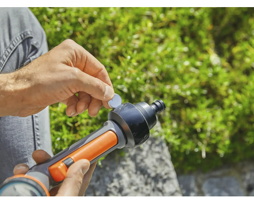 Eine Person legt eine Knopfzelle in eine Bewässerungspistole